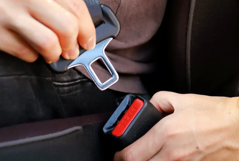 Hands engaging a seat belt latch plate into a buckle