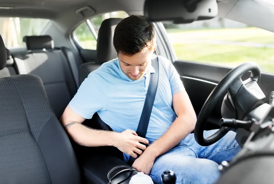 Seated driver with the seat belt fastened across the chest inside a vehicle cabin