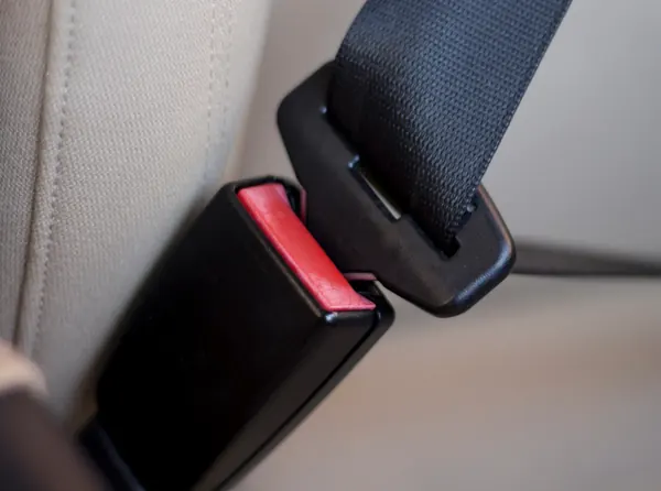 Seat belt tongue approaching a black buckle receiver
