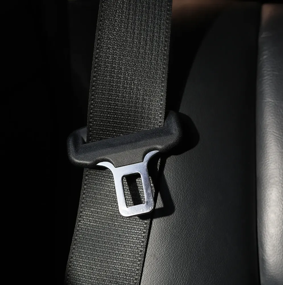 Seat belt webbing running past a shoulder guide with the latch plate in view
